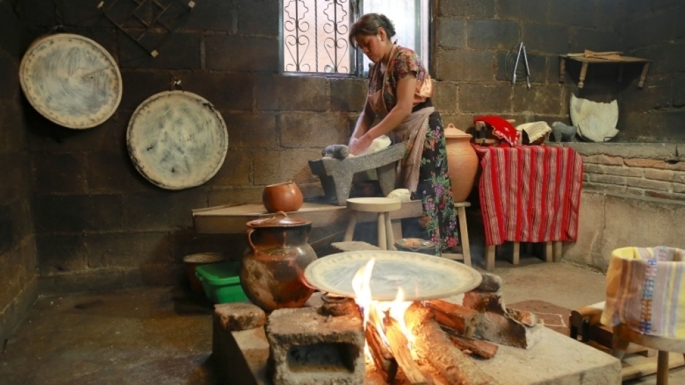 Una mujer cocina con leños en Chiapas, México. La falta de combustibles limpios para cocinar acarrea daños a la salud y el gasto de muchas horas para que las familias puedan recoger leña, lo que aleja a las mujeres de oportunidades de empleo y participaci